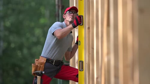 Man Leveling Wood Wall in Rural Construction Site