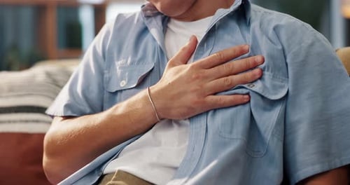 Man, hands and chest pain with heart burn for cardiac arrest, pressure or anxiety on sofa at home