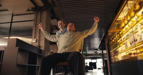 Coworkers Celebrate Success in Office Rolling Chair