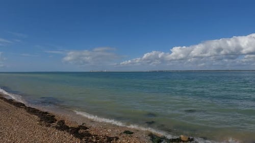Cristal clear water waves gently kissing the orange pebble beach in the Isle of Wight. Steady camera