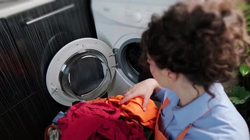Woman Puts Clothes in Washing Machine at Home