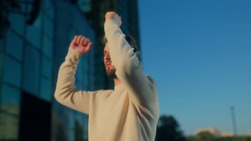 Man Puts On Headphones in an Urban Setting