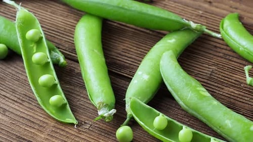 Fresh Green Pea Pods and Peas on Wood