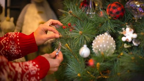 Woman Decorating Christmas Tree with Sparkly Ornaments