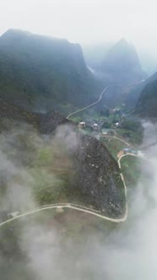 Vertical View of Rural Mountain Settlement in Northern Vietnam with Low Clouds and Rugged Terrain