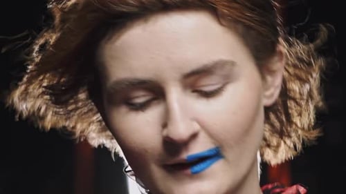 Gesicht einer trendigen attraktiven jungen blonden Frau mit modernem Make-up und halbblauen Lippen und zerzaustem Haar