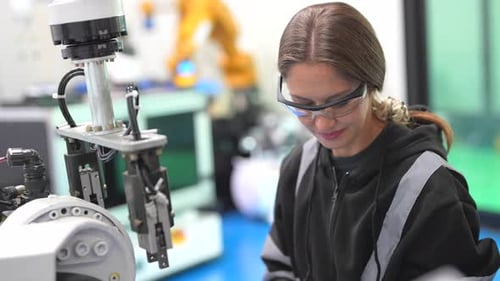 Une
technicienne programme un bras robotique avec une tablette numérique et un robot d'assemblage dans une usine. Appren