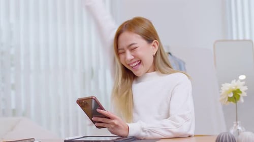 Woman Celebrates Good News on Smart Phone at Home