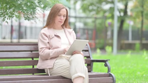 Woman Uses Tablet on Park Bench