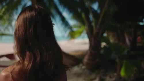 Woman Standing on Beach Next to Palm Trees