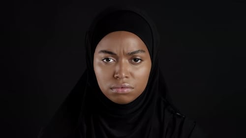Woman Wearing Hijab Stares into Camera on Black