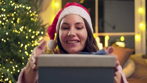 Excited Woman Opening Christmas Gift at Home