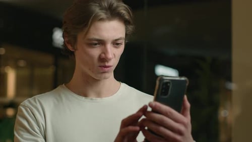 Young Man Celebrates While Looking at Cell Phone