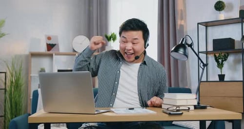 Man Cheers at Laptop in Indoor Setting