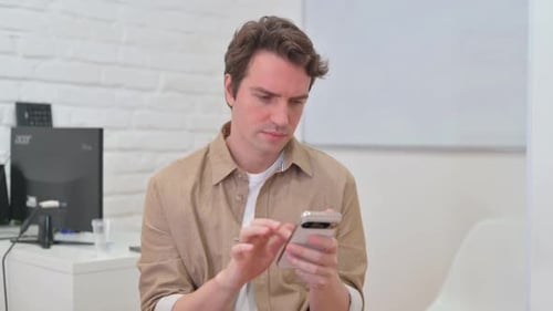 Porträt eines jungen kreativen Mannes, der das Telefon benutzt