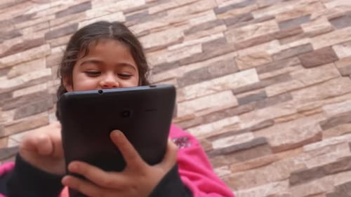 Little girl uses her smartphone to communicate with her parents. Screen fun at your fingertips. Enjo