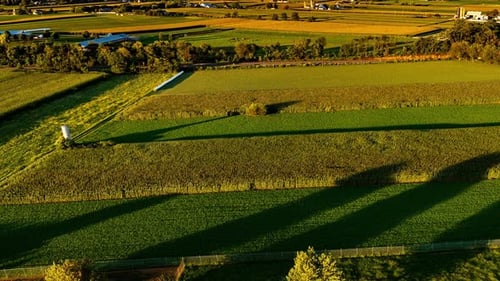 Lush green fields stretch across the landscape, with shadows creating captivating patterns as the
