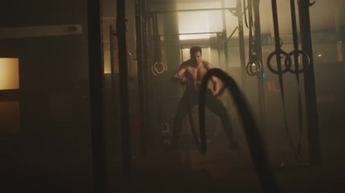 Muscular Man Battling Ropes in Gym