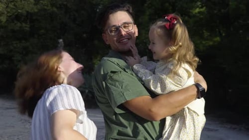 A young happy parents is playing with their adorable daughter in the city park