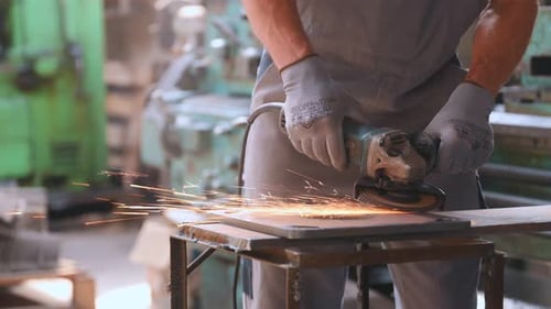 A worker at a heavy industry factory for the production of metal structures. A man in a uniform grin