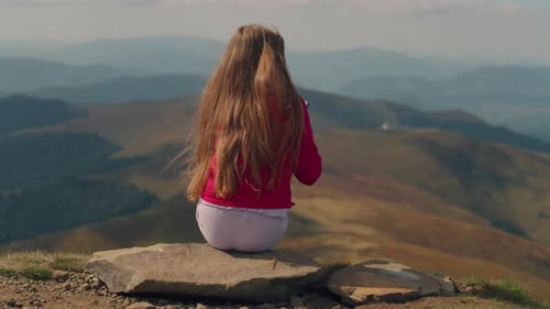 Girl Sits on Mountain Top Taking Pictures