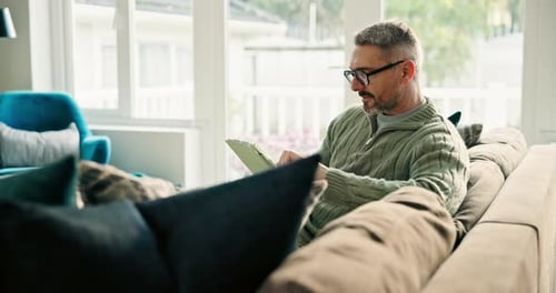 Man Using Tablet While Relaxing on Couch at Home