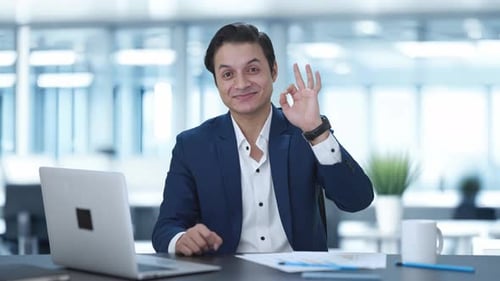 Smiling Businessman Gives Okay Gesture in Office