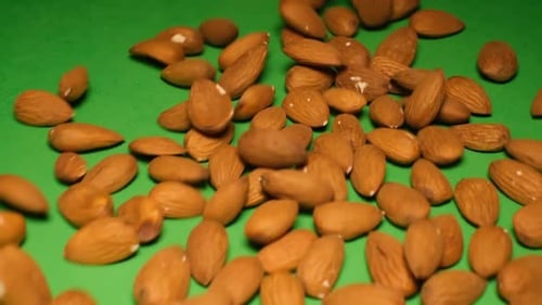 Almonds Falling on a Green Background