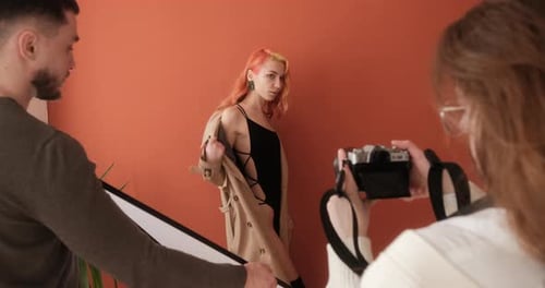 Female Redhead Model Acting During Photo Shoot in Studio with Photographer and Assistant