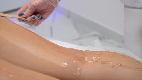 Master Beautician Applied Depilatory Gel to Young Woman Leg Before Laser Hair Removal Close Up