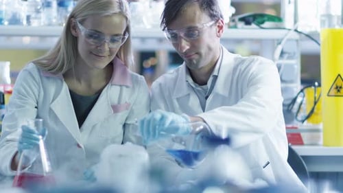 Two scientists are adding liquid to cold nitrogen in a laboratory.