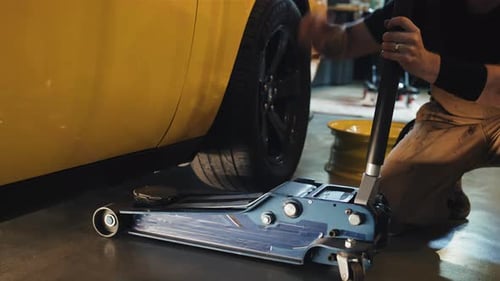 Mechanic Putting Jack Under Yellow Car, Moving Lever Lifting Car Body, Close Up