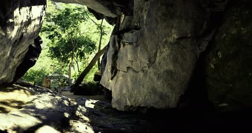Exploring a Rocky Cave Entrance Surrounded By Lush Greenery in Daylight