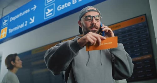 Airport Terminal Man Holding Plane Ticket Talking By Phone to Check Information