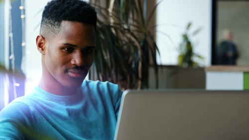 Concentrated Young African Man in Headphones with Laptop Computer Working