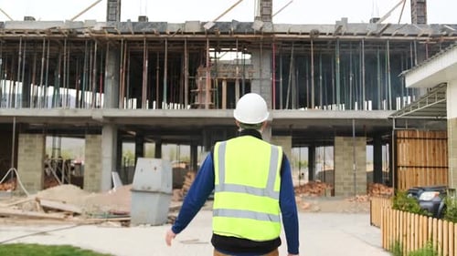 Mature experienced engineer comes to construction site puts on a safety helmet on head