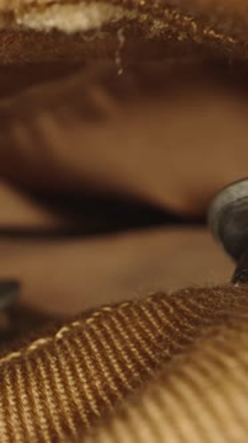 Vertical video. The camera glides through the zipper of the brown jeans with buttons. Dolly macro