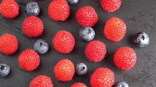 Ripe raspberries and blueberry close up rotate in a wooden bowl. Juicy fresh blueberry and raspber