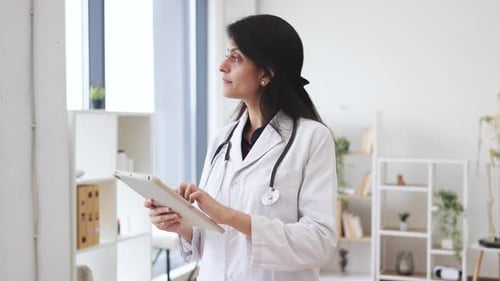 Therapist holding tablet while posing in doctor's office