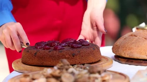 Woman Cuts Festive Plum Cake Outdoors