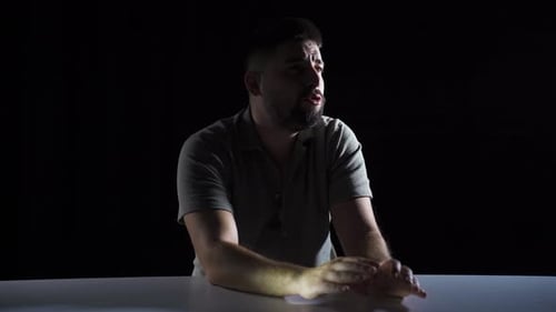 Man Gesturing and Speaking in Dark Interview Room