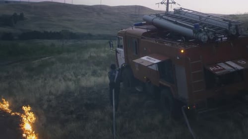 Firefighter Battling Blaze Near Truck in Rural Field