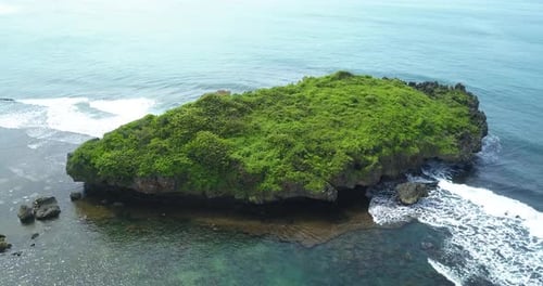 Drone view of huge coral rock with clusters of small rocks that surround it and crushing by the wave