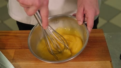 Nahaufnahme eines professionellen Kochs, der Eier in einer Schüssel in einer Restaurantküche mischt