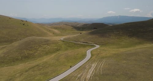 Aerial view of winding road near mountains, Italy.