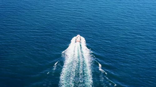 Aerial View of Fast Boat on a Deep Blue Sea with White Wakes