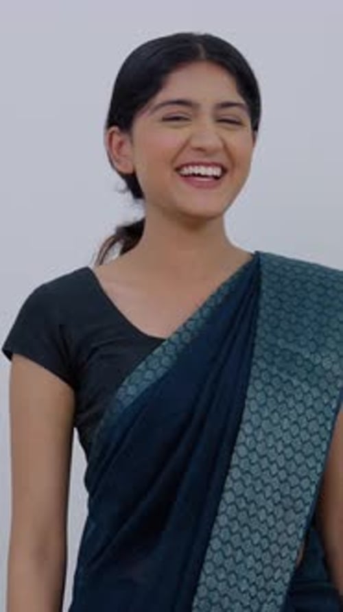 Smiling Woman Gestures Invitation in Front of White Wall