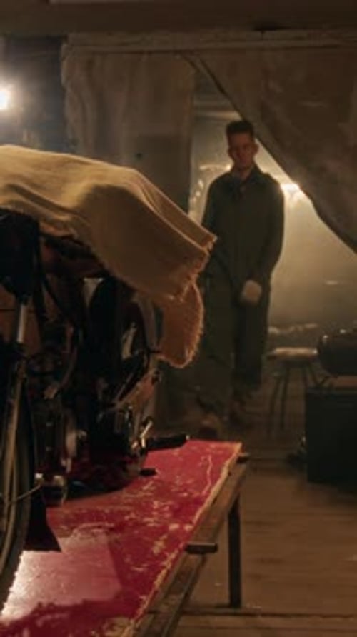 Mechanic Taking Off Cover from Vintage Motorcycle in Garage