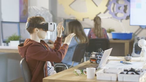 In a Computer Science Class Boy Wearing Virtual Reality Headset Works on a Programing Project.