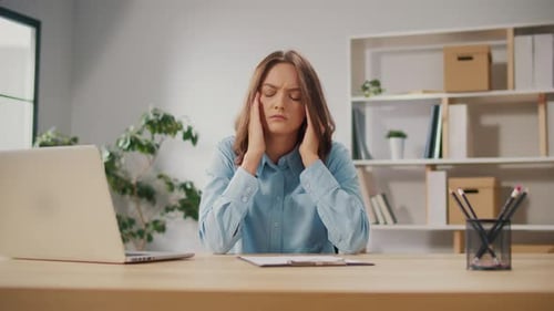 Portrait of a Tired Young Woman With a Headache Due to Overwork at the Computer